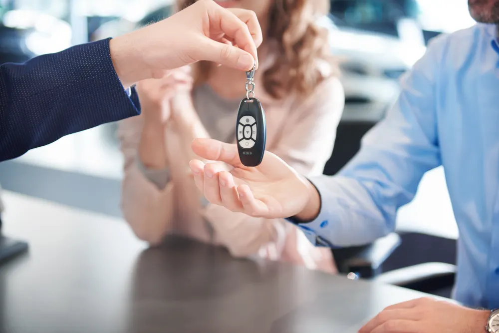 Autoschlüssel wird über einen Tisch an eine Kundin übergeben